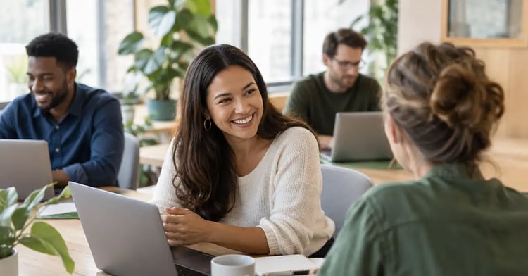 A small team talking and working together at a shared desk in a bright, welcoming office